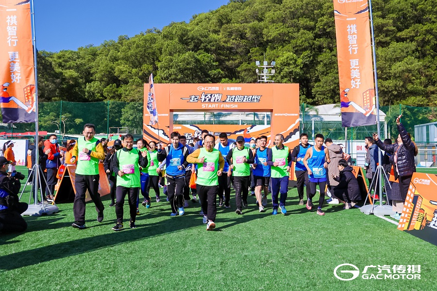 Participants wearing green vest and jogging with orange backdrop at the 2021 GAC Motor EMPOW55 run